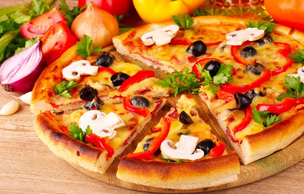 پیتزا و سبزیجات در زمینه چوبی