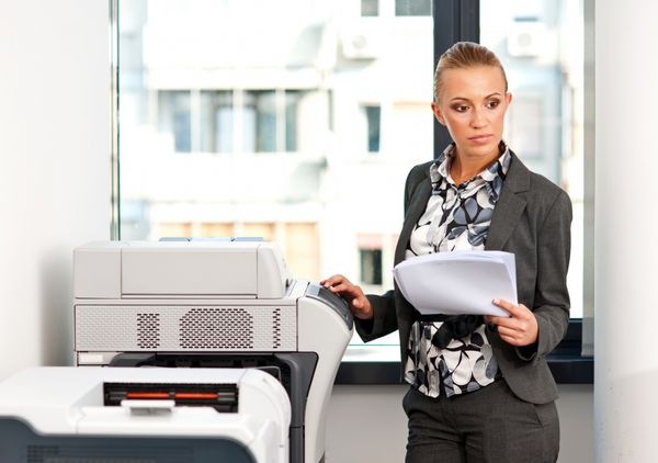 زن جذابی که روی دستگاه کپی در دفتر کار می کند