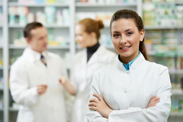 زن شیمیدان داروساز شاد که در داروخانه داروخانه ایستاده است