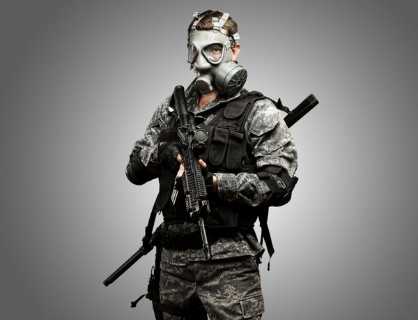 پرتره سرباز جوان با ماسک گاز و تفنگ در پس زمینه خاکستری