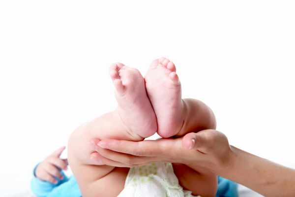 نمای نزدیک از دست مادری که پای نوزاد را در دست گرفته است