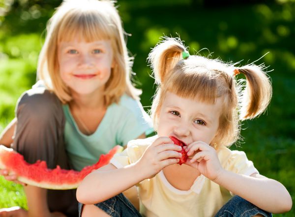 بچه های شاد در حال خوردن هندوانه در فضای باز در پارک بهار