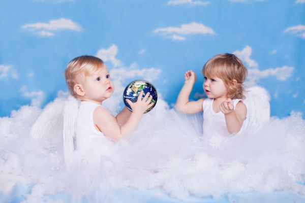 دو کودک کوچک به شکل فرشته در ابرها با سیاره زمین اسباب بازی پوگراف استودیویی