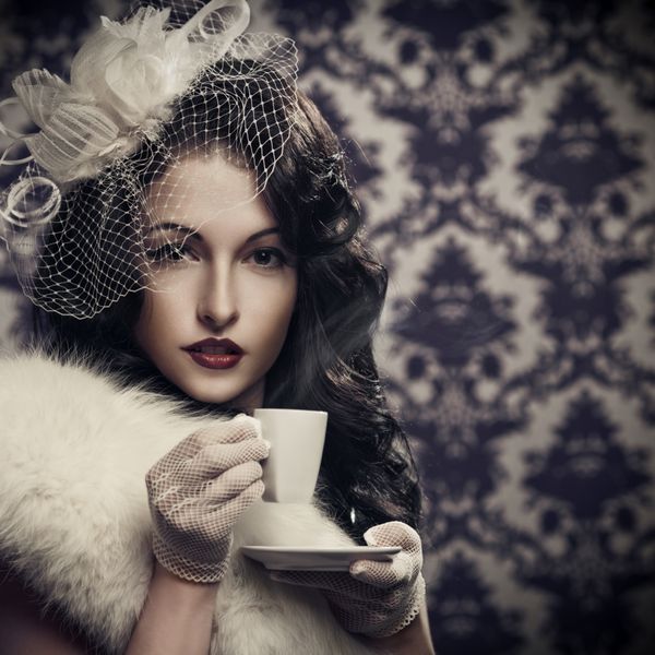 خانم جوان زیبای رترو در حال نوشیدن قهوه