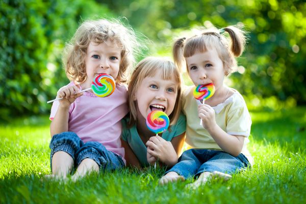 گروهی از کودکان شاد در حال خوردن قطره های میوه در فضای باز در پارک بهار