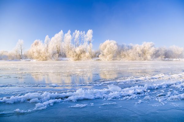 رودخانه یخبندان زمستانی که با طلوع خورشید روشن شده است
