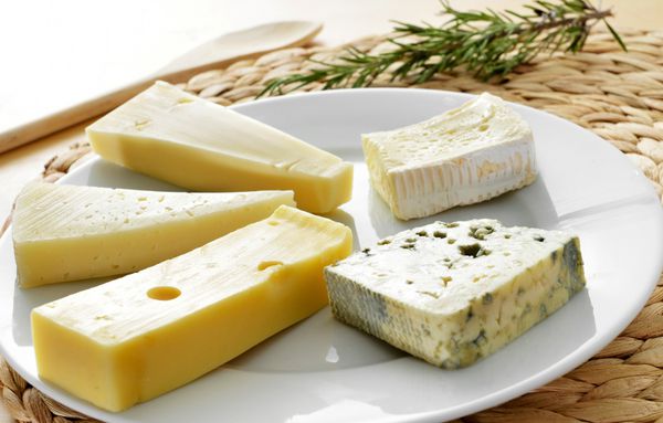 نمای نزدیک از یک بشقاب با مجموعه ای از پنیر مانند پنیر امانتال پنیر آبی یا پنیر بری