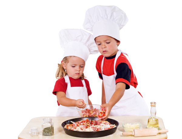 دو بچه با لباس سرآشپزها در حال تهیه پیتزا - ایزوله