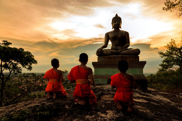 مجسمه بودا و تازه کار در غروب آفتاب در سارابوری تایلند