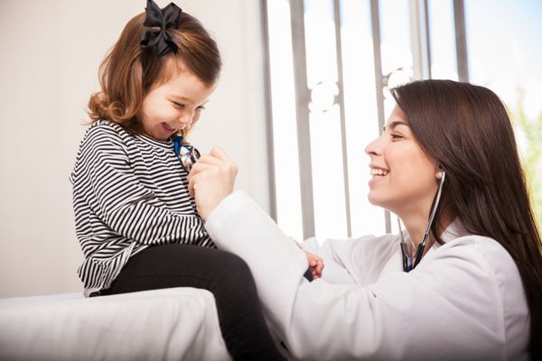 متخصص اطفال اسپانیایی زیبا که تنفس و لبخند یک دختر بچه را بررسی می کند