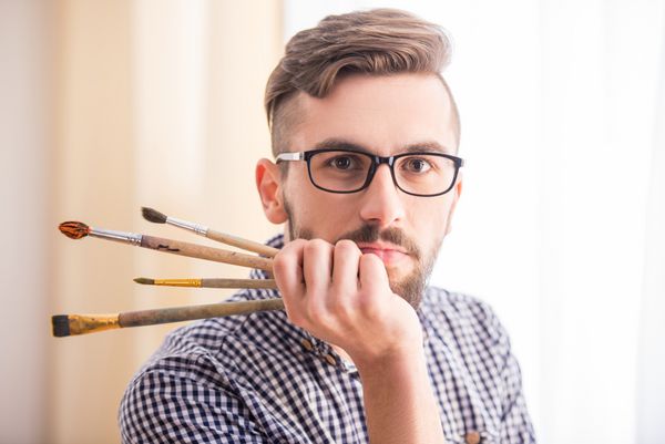 پرتره هنرمند مرد جوان با قلم مو برای نقاشی