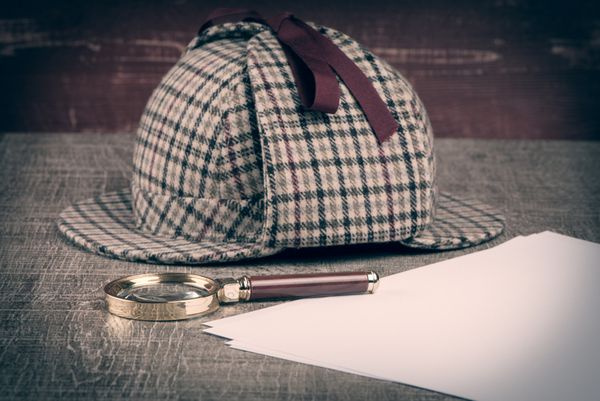 کلاه آهو یا شرلوک و ذره بین روی میز چوبی قدیمی