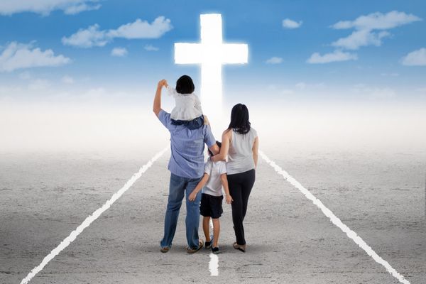 نمای پشت خانواده کمی شاد که در جاده ایستاده اند و یک صلیب را دنبال می کنند