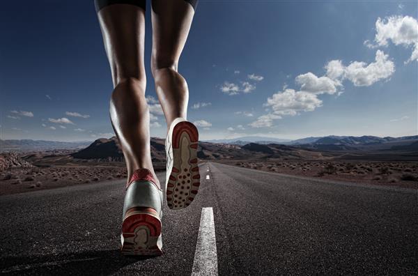پس زمینه ورزشی پاهای دونده در حال دویدن در نزدیکی جاده روی کفش