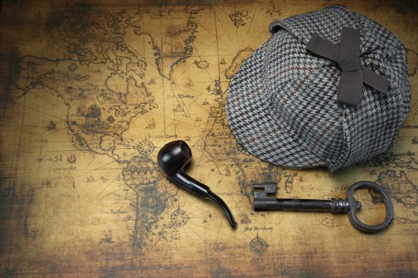 کلاه شرلوک هلمز deerstalker کلید قدیمی و پیپ سیگار کشیدن در پس‌زمینه نقشه دنیای قدیم نمای بالای سر مفهوم تحقیق