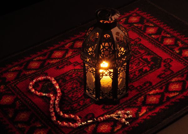 فانوس عربی روی فرش قرمز با تسبیح چوبی