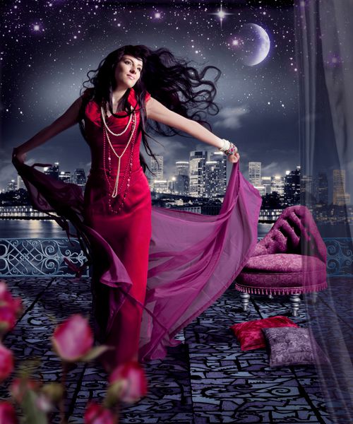 زن زیبا با لباس شب قرمز در یک تراس با خط افق یک شهر در پشت