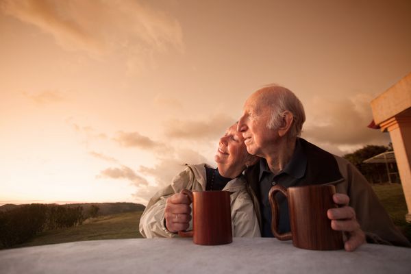 زوج سالخورده خندان که هنگام غروب آفتاب بیرون نشسته اند