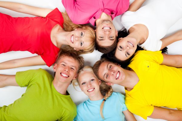گروهی از جوانان دراز کشیده روی زمین در دایره دانش‌آموزان نوجوان لبخند شاد با زاویه دید بالای پس‌زمینه سفید