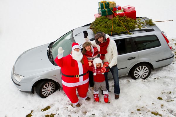 در انتظار کریسمس بابا نوئل - خانواده در حال حمل درخت کریسمس و هدایایی روی سقف ماشین هستند