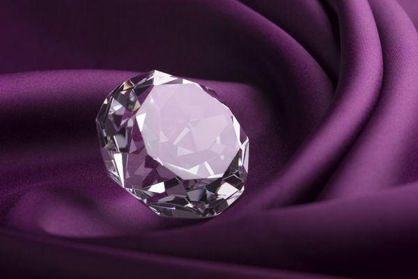 الماس شفاف گران قیمت براق روی پارچه ابریشمی بنفش
