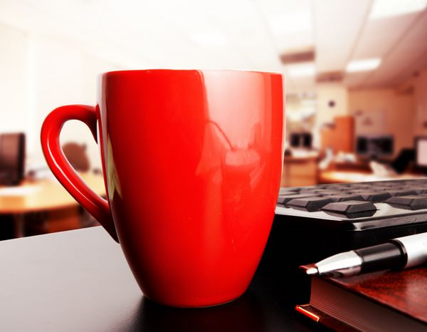 فنجان قهوه قرمز در دفتر