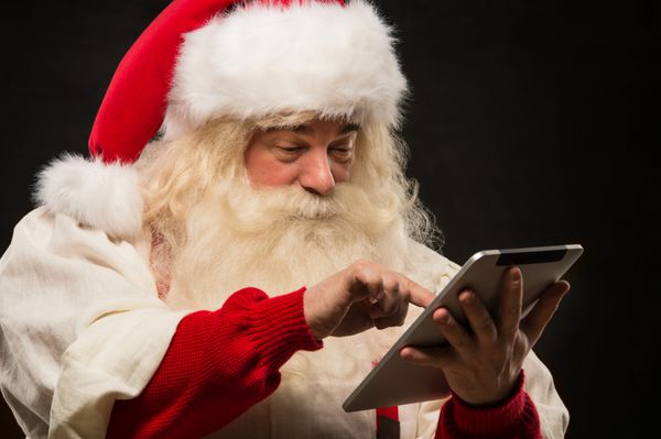 بابا نوئل با استفاده از رایانه لوحی برای گشت و گذار در اینترنت و برقراری ارتباط در رسانه های اجتماعی با کودکان