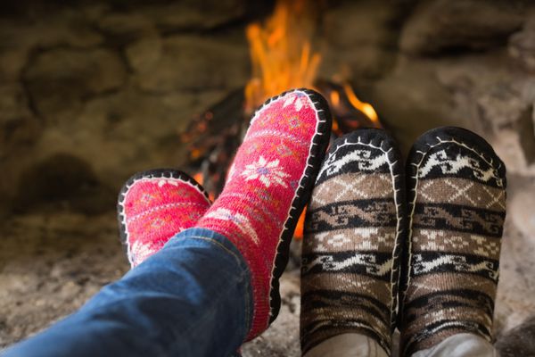 نمای نزدیک از پاهای زوج عاشقانه در جوراب جلوی آتشفشان در فصل زمستان در خانه
