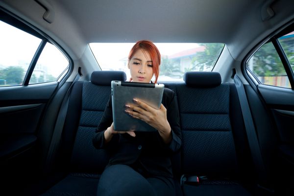 زن جوان آسیایی تجاری داخل ماشینش با استفاده از تبلت