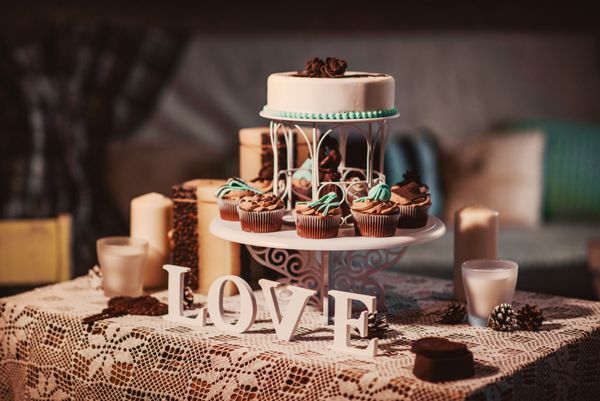 عاشق حروف چوبی روی میز تزئین شده تعطیلات با شمع و کیک است