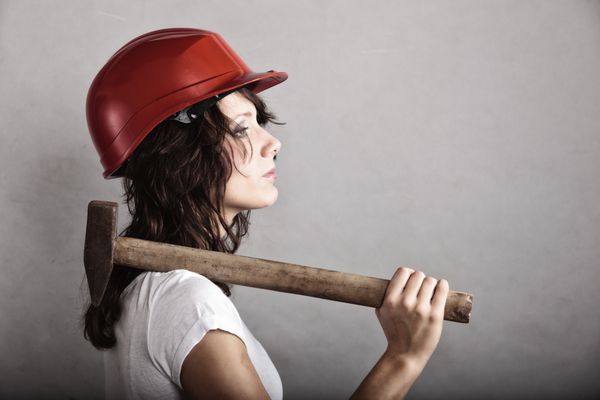 برابری و فمینیسم دختری با کلاه ایمنی که ابزار چکشی در دست دارد زن جذابی که به عنوان کارگر ساختمانی کار می کند