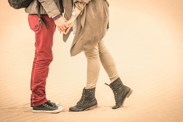 مفهوم عشق در پاییز - زوج عاشق جوان در حال بوسیدن در فضای باز با نمای نزدیک روی پاها و کفش ها - نگاه فیلتر شده نوستالژیک اشباع شده