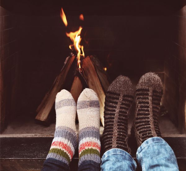 نمای نزدیک از پاهای عاشقانه یک زن و شوهر با جوراب در مقابل شومینه در فصل زمستان در خانه