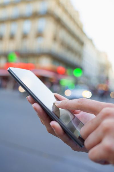 زن از تلفن همراه خود در خیابان در پاریس استفاده می کند