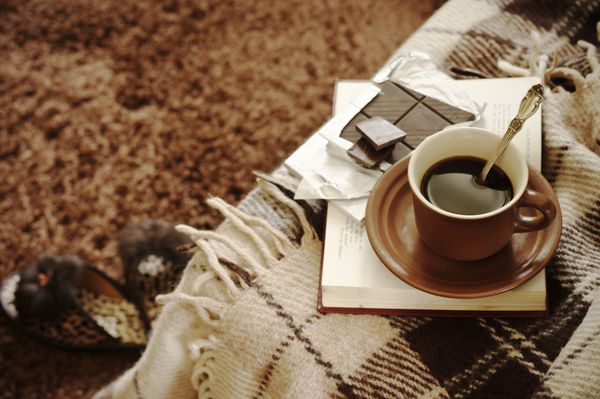 چهارخانه پشمی فنجان قهوه کتاب و دمپایی روی فرش پشمالو نمای بالا