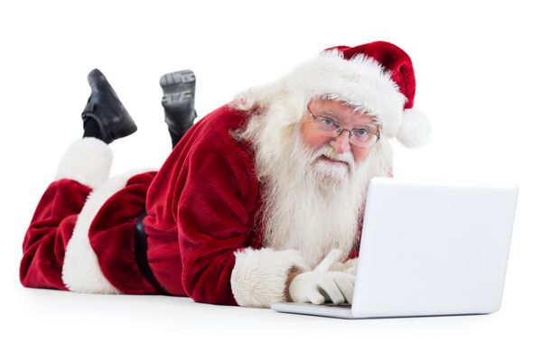 بابا نوئل در مقابل لپ تاپ خود در پس زمینه سفید دراز کشیده است