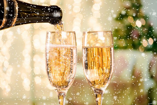 دو لیوان شامپاین با ستاره و برف در پس‌زمینه اتاق نشیمن با درخت کریسمس