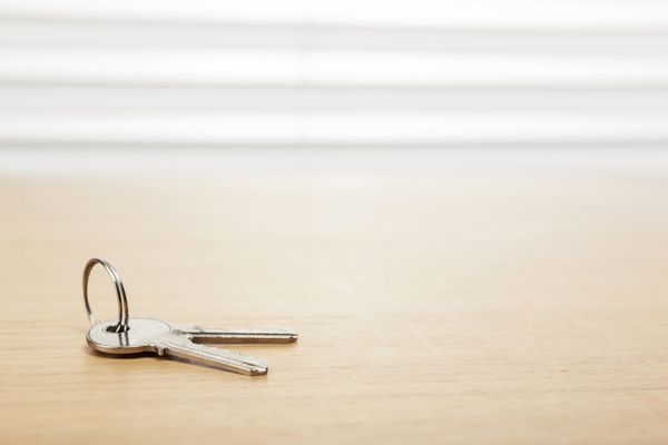 کلید نقره ای روی میز اداری چوبی میز پشت پرده سفید