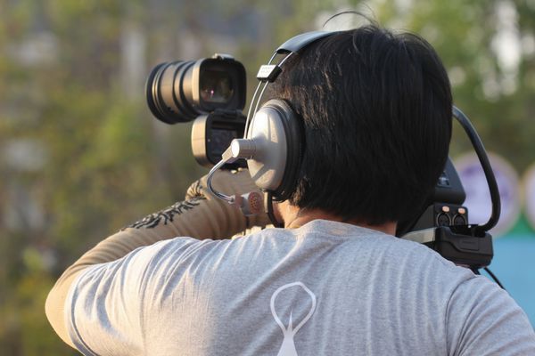 مرد آسیایی با دوربین فیلمبرداری گزارشگر ویدئویی فیلمبردار فیلمبردار جوان در فضای باز