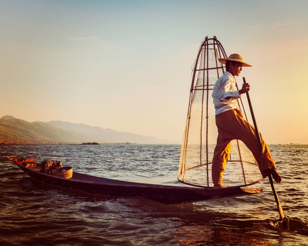 افکت رترو کلاسیک تصویری به سبک هیپستر فیلتر شده از نقطه عطف جاذبه سفر میانمار - ماهیگیر سنتی برمه ای در دریاچه اینل میانمار معروف به سبک متمایز قایقرانی با یک پا
