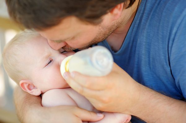 نوزاد پسر شایان ستایش در حال نوشیدن شیر از شیشه در دستان پدر