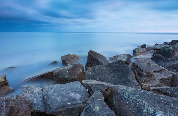 چشم انداز زیبای دریای بالتیک با موج شکن سنگی مناظر آرام با نوردهی طولانی مدت با آسمان تار و آب