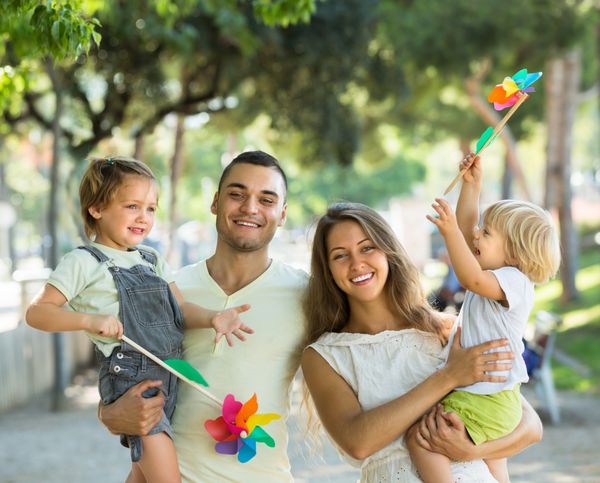 پدر و مادر جوان شاد نگه داشتن بچه ها با لوازم بادی اسباب بازی در روز تابستان