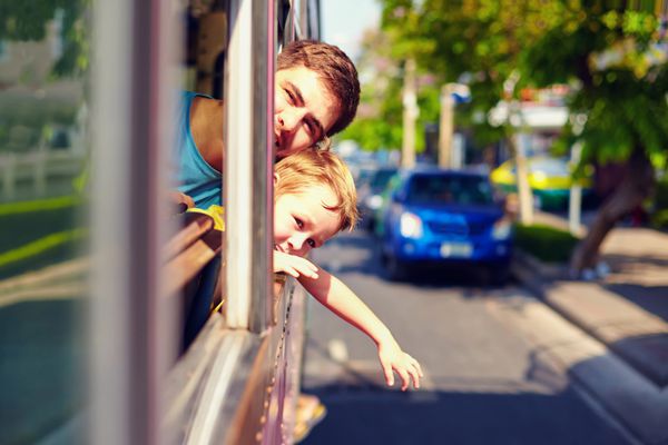 پدر و پسر در حال سفر با اتوبوس عمومی بدون پنجره از طریق شهر آسیایی
