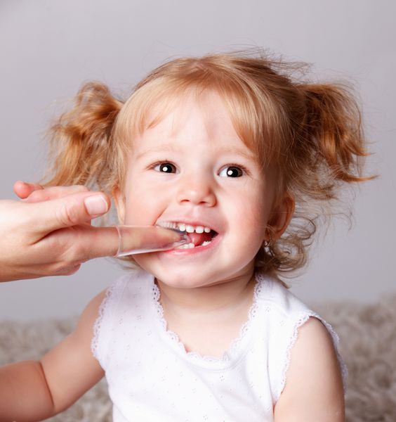 کودک کوچک خوشحالی که دندان هایش را با دندان های انگشتی مسواک می زند