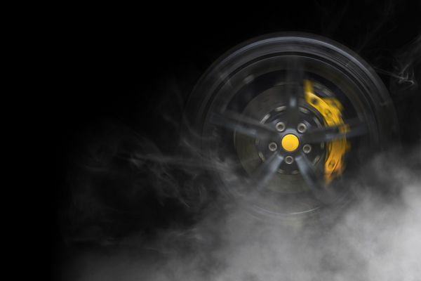 چرخ ماشین اسپرت عمومی جدا شده با شکسته های زرد در حال حرکت و کشیدن سیگار روی پس زمینه سیاه