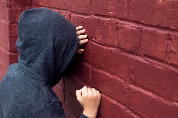 پسر نوجوان غمگین و افسرده نگران کودک در حال گریه در نزدیکی دیوار آجری