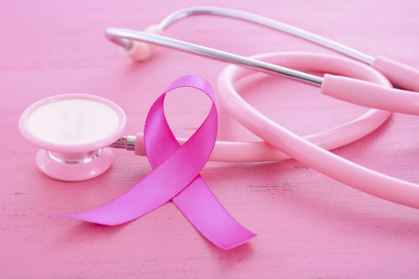 روبان صورتی آگاهی سرطان سینه زنانه با گوشی پزشکی روی میز چوبی صورتی با نماد روبان