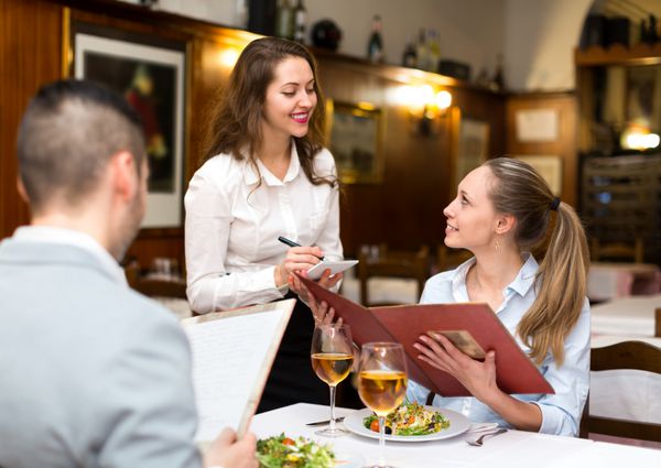 پیشخدمت مهمان نواز که از یک زن و شوهر در یک رستوران روستایی سفارش می گیرد