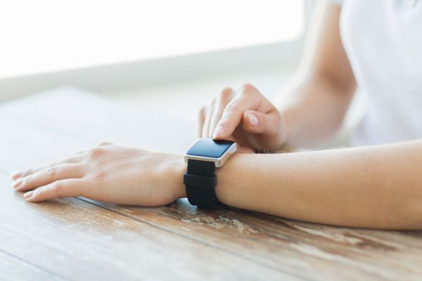 مفهوم کسب و کار فناوری و مردم - از نزدیک دست های زن که ساعت هوشمند را در خانه تنظیم می کنند